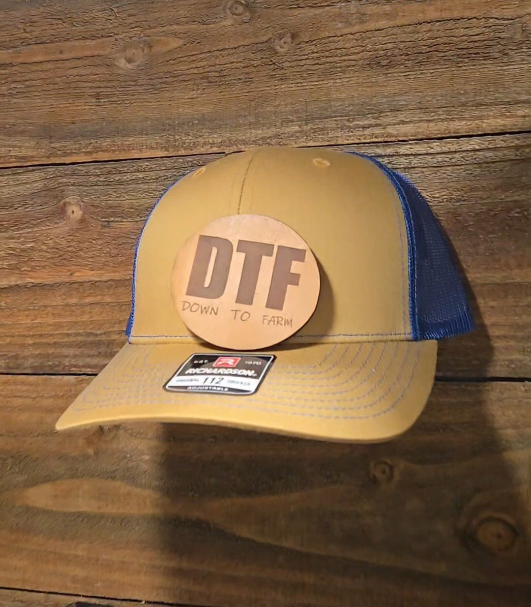 Yellow and blue cap with 'DTF' logo (Not attached yet) on a wooden background